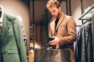 A young man is buying clothes, paying with cash at a shop